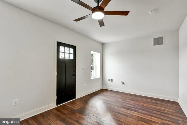 an empty room with wooden floor ceiling fan and windows