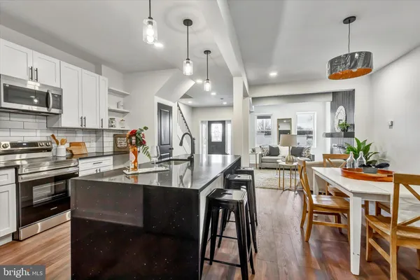 a kitchen with stainless steel appliances granite countertop a stove a sink a dining table and chairs with wooden floor