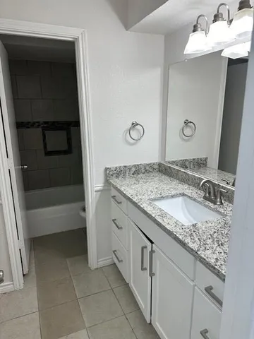 a bathroom with a granite countertop sink and a mirror