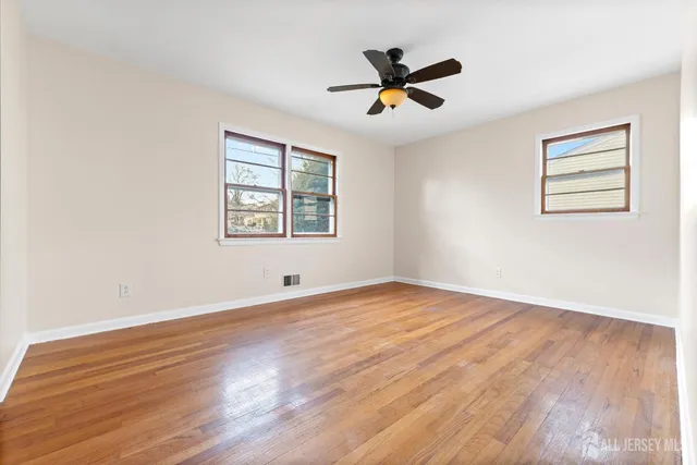 a view of empty room with wooden floor and fan