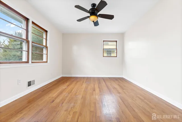 a view of an empty room with window and wooden floor