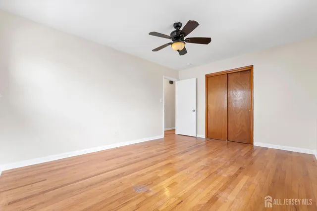 a view of empty room with wooden floor and ceiling fan