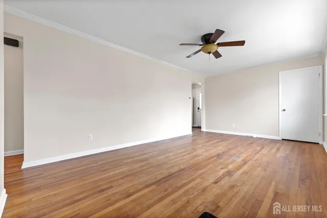 an empty room with wooden floor ceiling fan and windows
