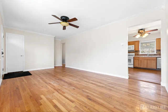 a view of empty room with wooden floor and ceiling fan