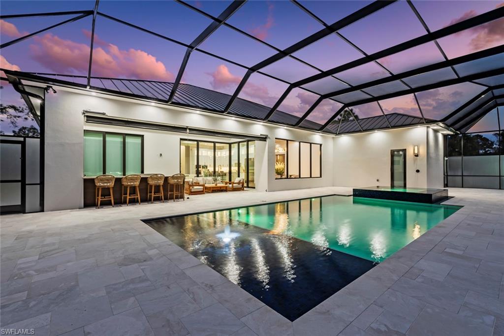 722 19th Street Southwest Naples, FL 34117 - Photo 43 of 47 Pool at dusk with a lanai, a patio area, outdoor lounge area, and exterior bar