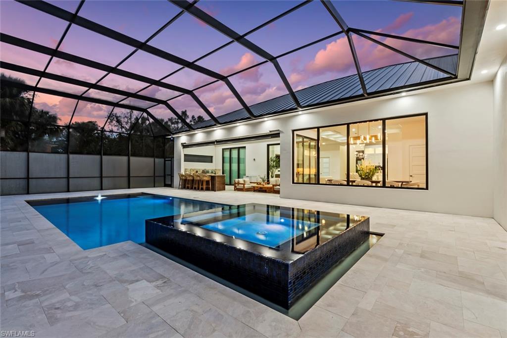 722 19th Street Southwest Naples, FL 34117 - Photo 44 of 47 Pool at dusk with an in ground hot tub, a lanai, and a patio area
