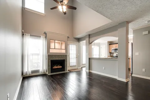 an empty room with wooden floor fireplace and windows