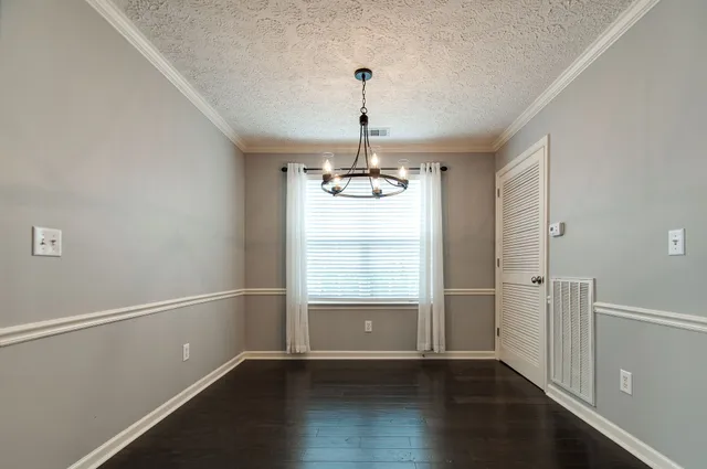 an empty room with wooden floor cabinet and windows