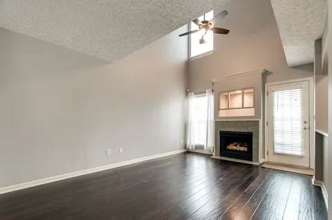 an empty room with wooden floor fireplace and windows