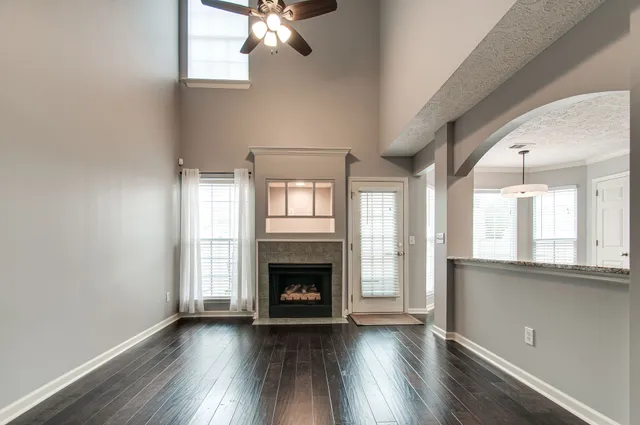 an empty room with wooden floor fireplace and windows