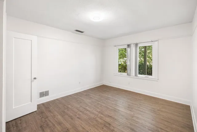 a view of an empty room with wooden floor & closet