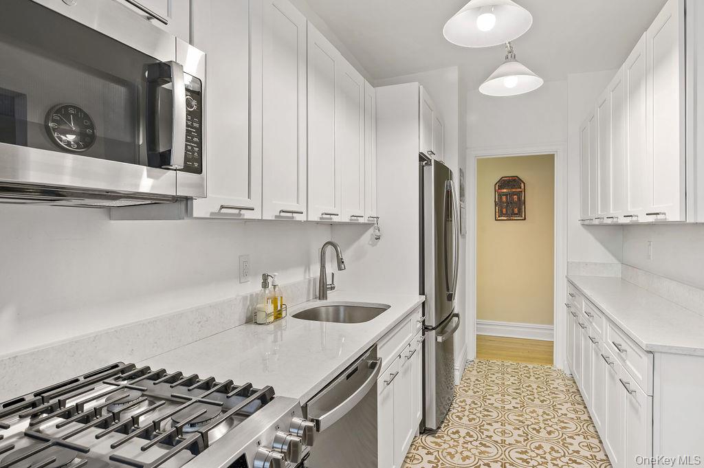 43 Calton Road, Unit 5C New Rochelle, NY 10804 - Photo 12 of 32 Kitchen with stainless steel appliances, light stone counters, white cabinetry, and hanging light fixtures