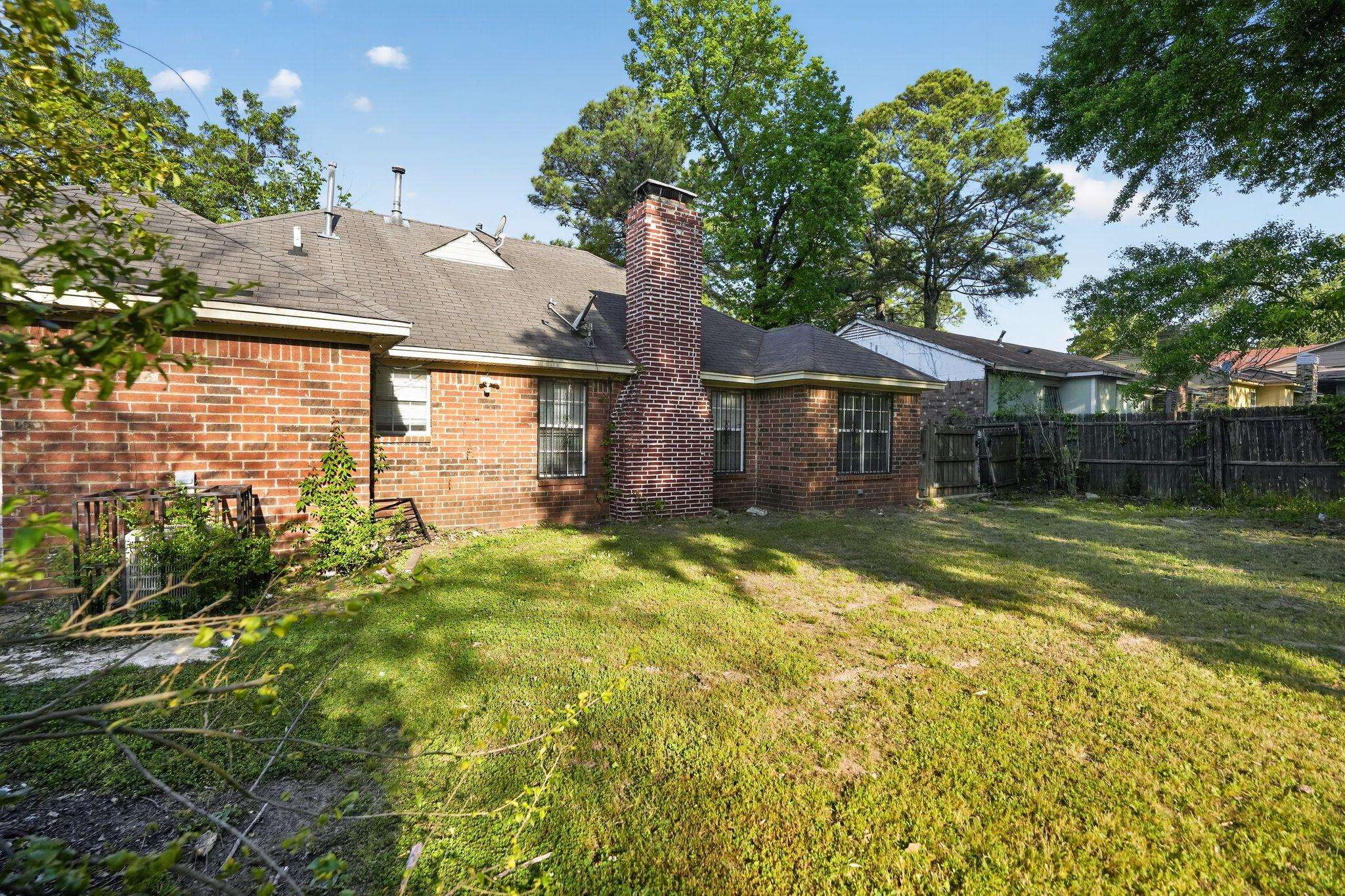 3820 Clarke Road Memphis, TN 38115 - Photo 26 of 30 Rear view of house featuring brick siding, a fenced backyard, a chimney, and roof with shingles