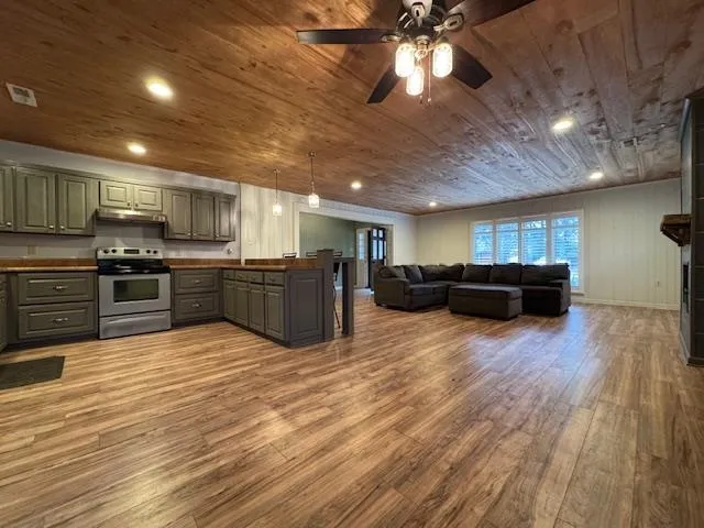 a kitchen with stainless steel appliances kitchen island granite countertop a stove and a wooden floors