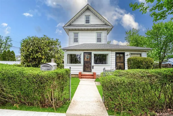 a front view of a house with a yard and potted plants