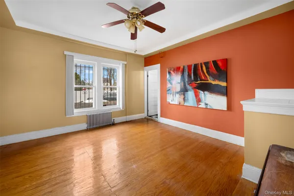 a view of an empty room with window and wooden floor