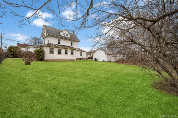 a view of a house with a big yard and large tree