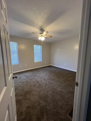 an empty room with windows and fan