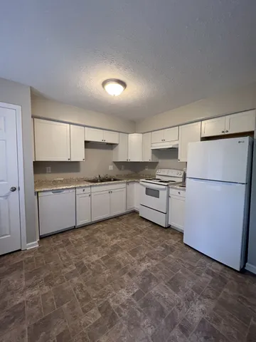 a kitchen with stainless steel appliances granite countertop a refrigerator sink and white cabinets