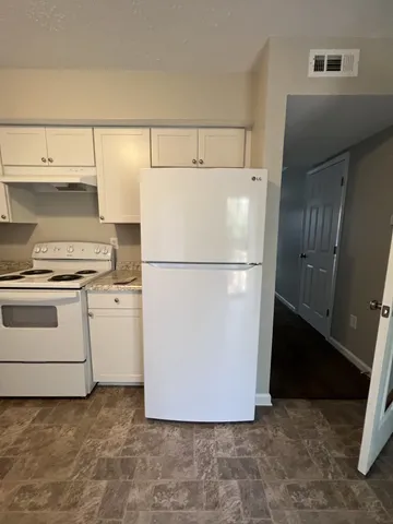 a white refrigerator freezer and a stove sitting inside of a kitchen