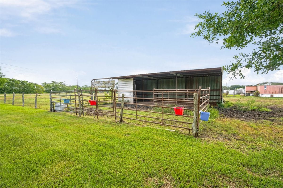 765 Norcross Road Wallis, TX 77485 - Photo 30 of 42 This photo shows a small, fenced livestock pen with a metal shelter, ideal for housing animals. It's set on a lush green field, offering ample outdoor space.