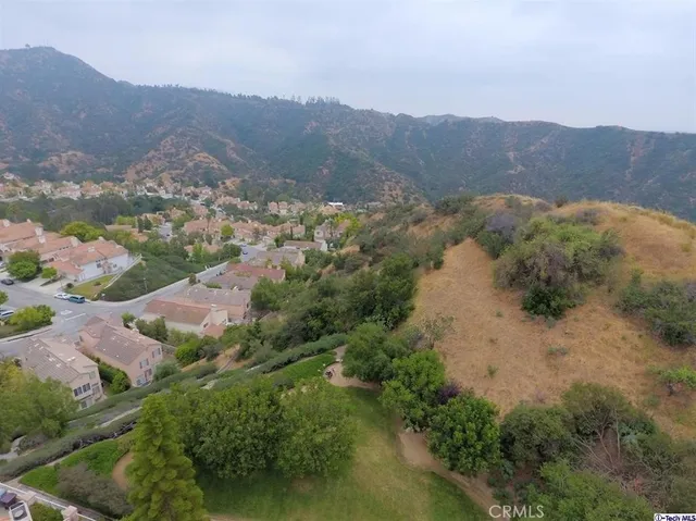 an aerial view of houses with a street and green space
