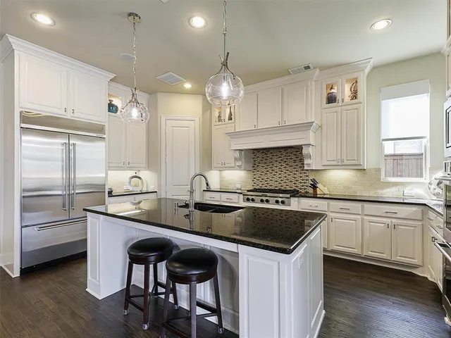 a kitchen with granite countertop a sink stove and refrigerator