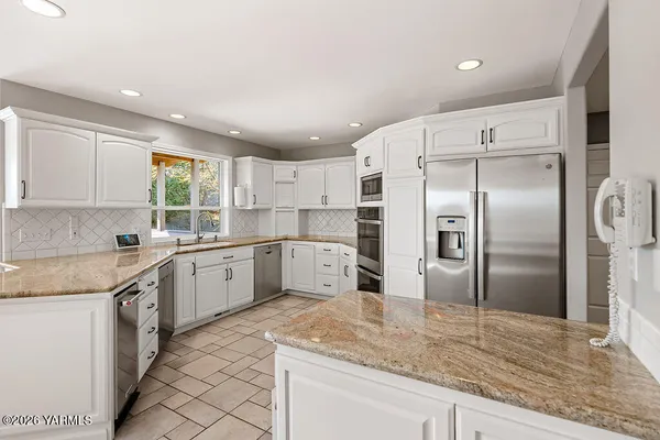 a kitchen with granite countertop a refrigerator sink and cabinets