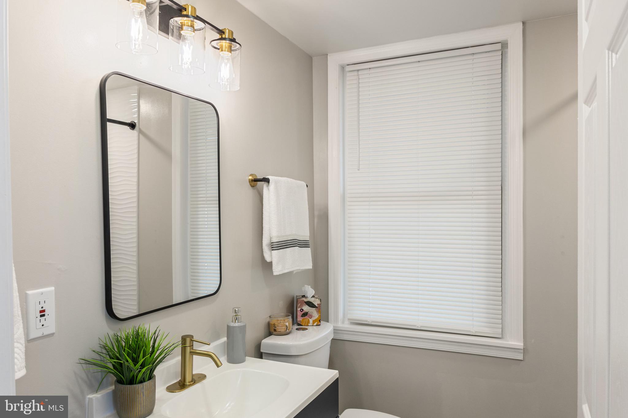 4042 6th Street Baltimore, MD 21225 - Photo 11 of 31 a bathroom with a sink a mirror and a shower