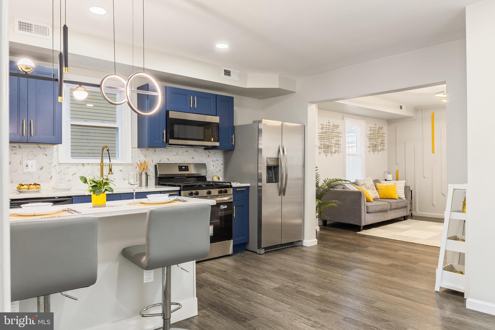 4042 6th Street Baltimore, MD 21225 - Photo 9 of 31 a kitchen with stainless steel appliances a stove a refrigerator a sink a oven with a dining table and chairs