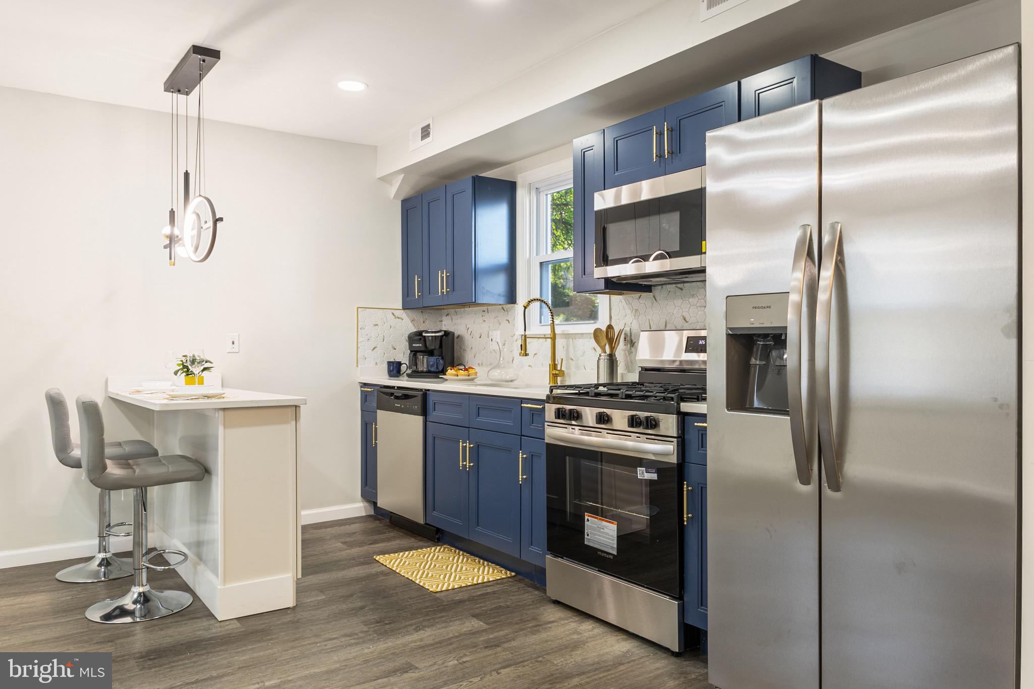 4042 6th Street Baltimore, MD 21225 - Photo 10 of 31 a kitchen with stainless steel appliances granite countertop a refrigerator a stove a sink dishwasher a dining table and chairs with wooden floor