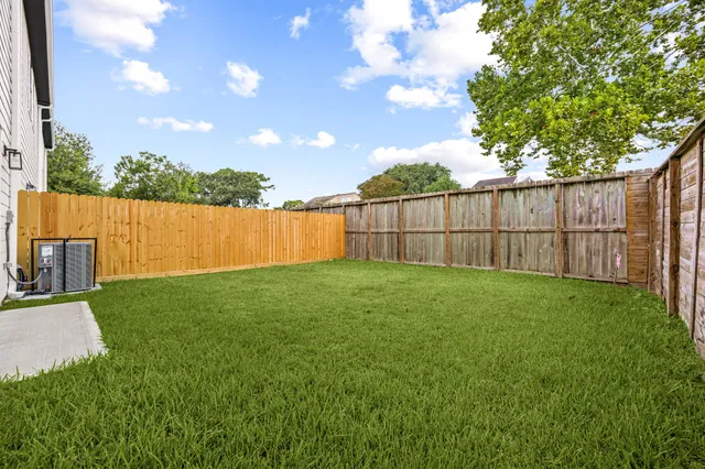 a view of a backyard with a tree and wooden fence