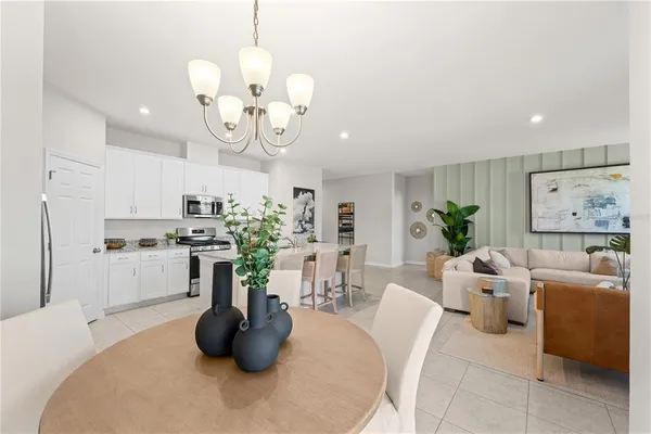 a kitchen with stainless steel appliances kitchen island granite countertop a white table a chairs a sink and cabinets
