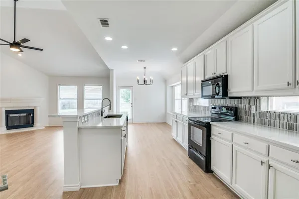a kitchen with kitchen island granite countertop a sink cabinets and wooden floor