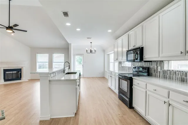 a kitchen with kitchen island granite countertop a sink cabinets and wooden floor