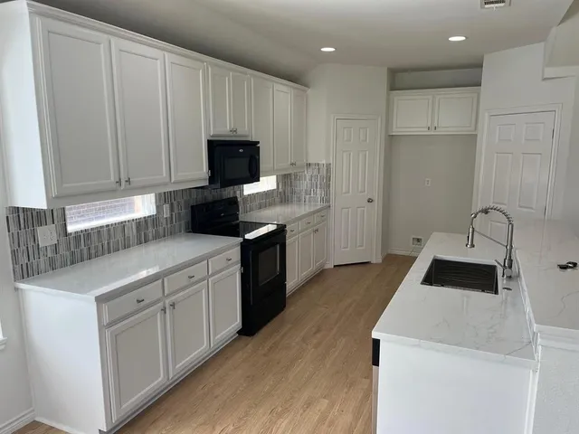 a kitchen with a sink a stove and cabinets