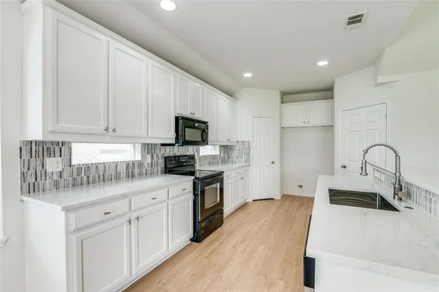 a kitchen with white cabinets and sink