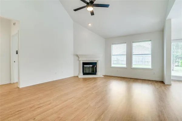 an empty room with wooden floor chandelier fan and windows