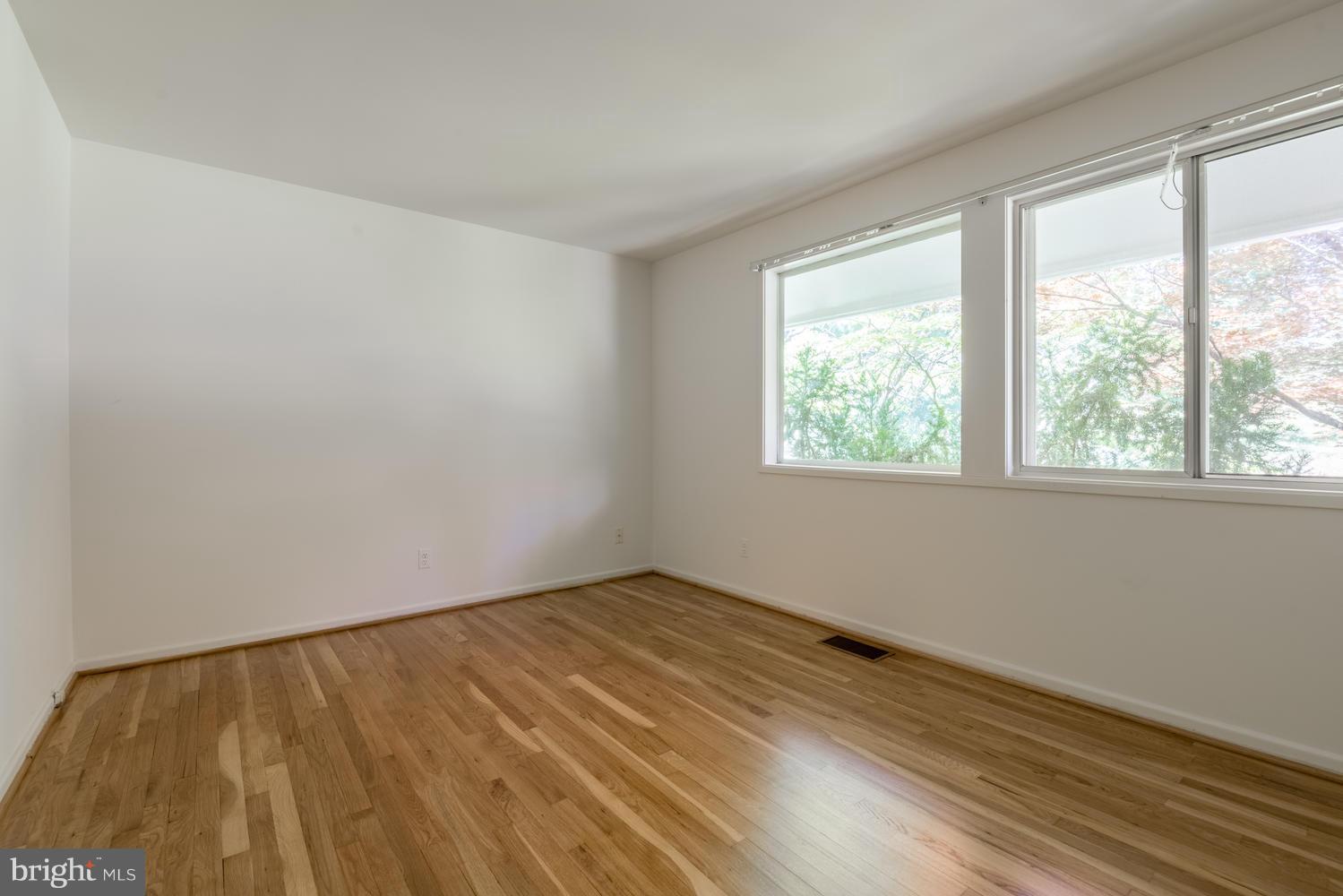6805 Persimmon Tree Road Bethesda, MD 20817 - Photo 18 of 30 a view of an empty room with wooden floor and a window