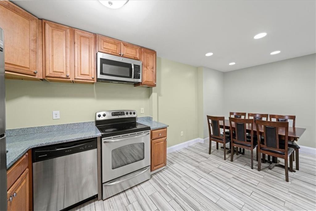 3087 Colonial Way, Unit J Atlanta, GA 30341 - Photo 6 of 21 a kitchen with stainless steel appliances granite countertop a stove top oven a dining table and chairs with wooden floor