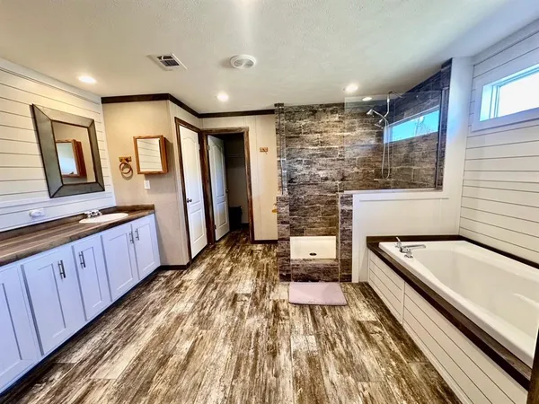 a spacious bathroom with a granite countertop tub sink and wooden floor