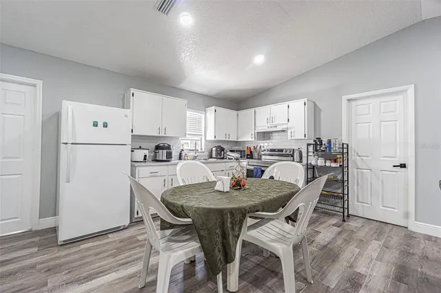 a kitchen with stainless steel appliances granite countertop a stove a sink dishwasher a microwave oven and a dining table with wooden cabinet