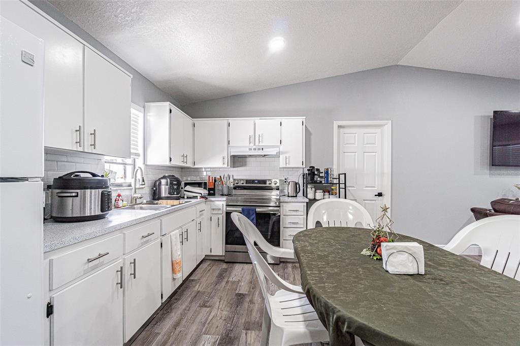 3482 Dow Lane Spring Hill, FL 34609 - Photo 14 of 30 a kitchen with stainless steel appliances granite countertop a stove a sink dishwasher a microwave oven and a dining table with wooden cabinet