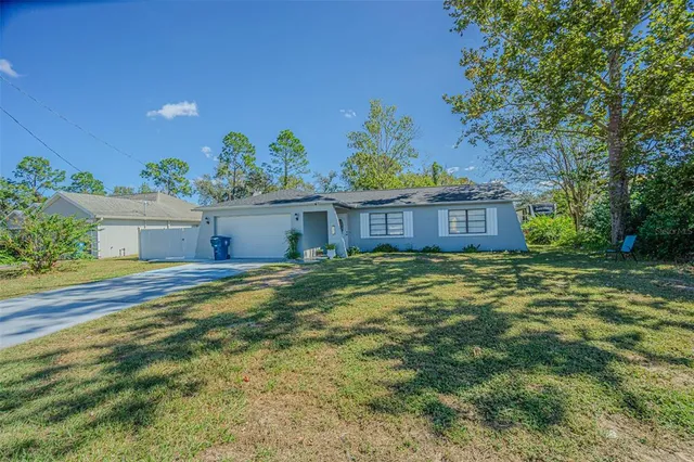 a view of a house with a yard and a large tree