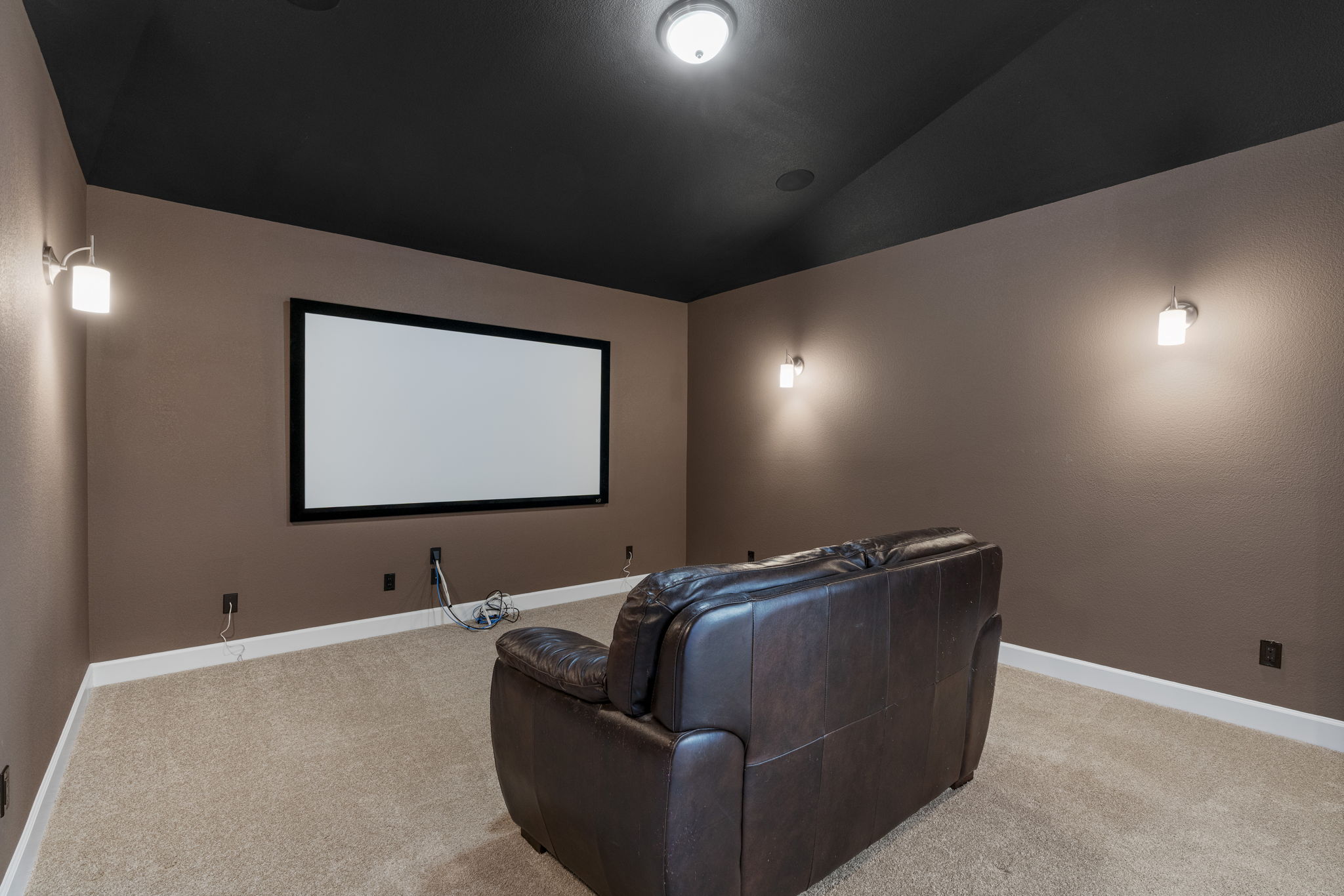 110 Topaz Circle Dripping Springs, TX 78620 - Photo 33 of 40 Double doors off the game room open into the media room with a built-in screen and wall sconce lighting.
