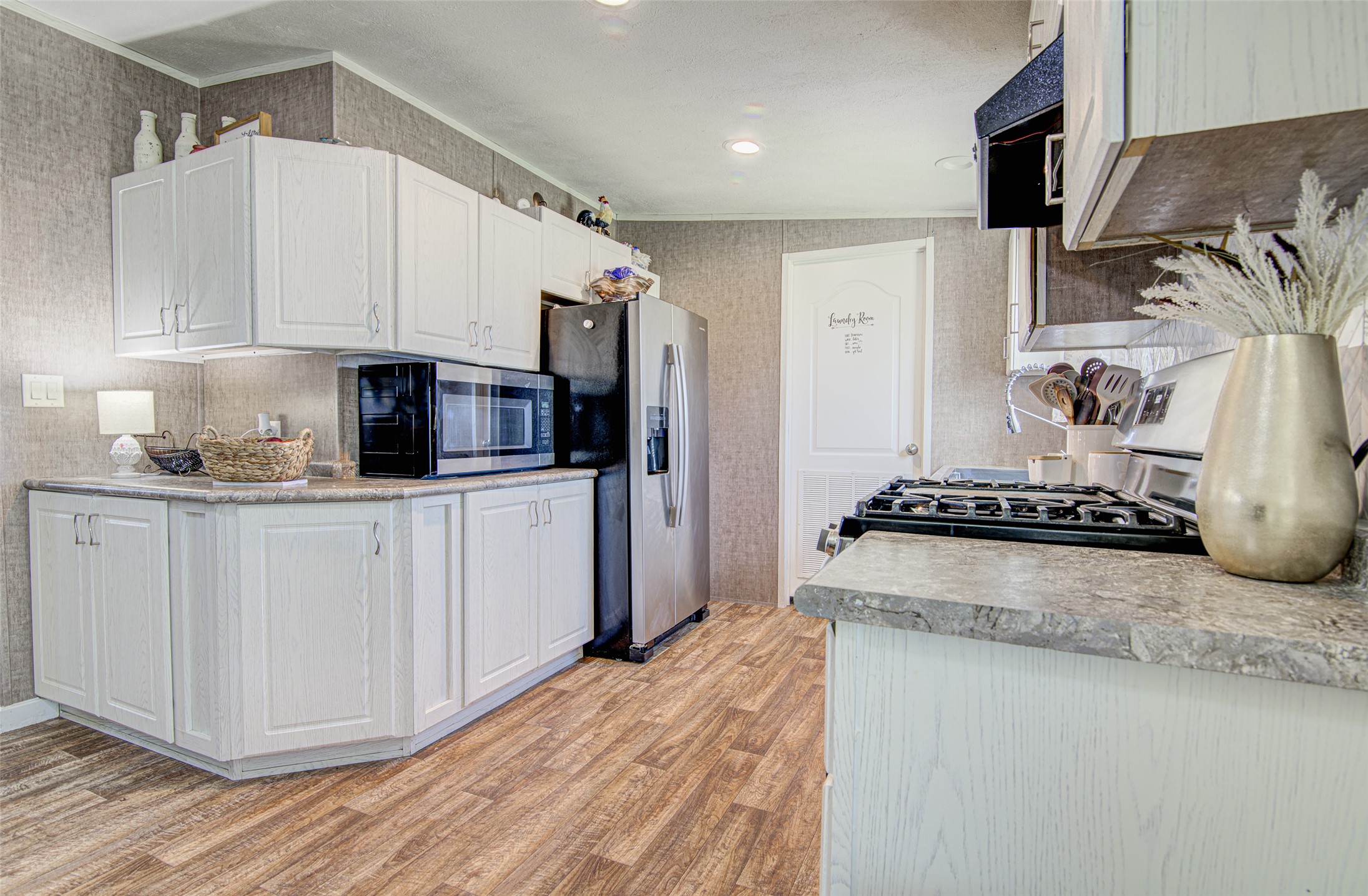 445 Rancho Linda Drive Lockhart, TX 78644 - Photo 12 of 26 A functional kitchen features wood-look flooring and ample cabinetry for storage.