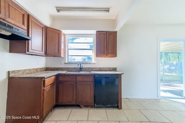 a kitchen with a sink a stove cabinets and a window