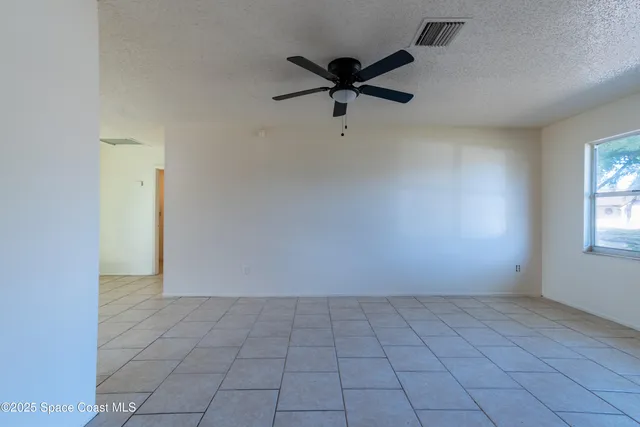 an empty room with a ceiling fan and windows