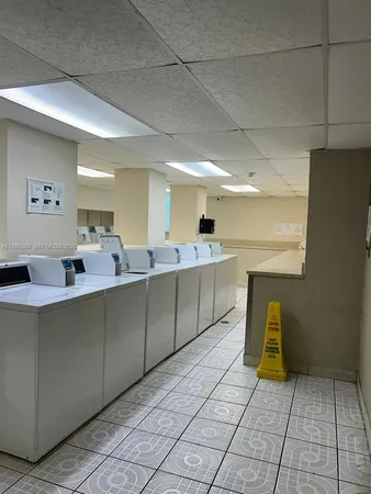 a view of an empty room with wooden floor and a kitchen