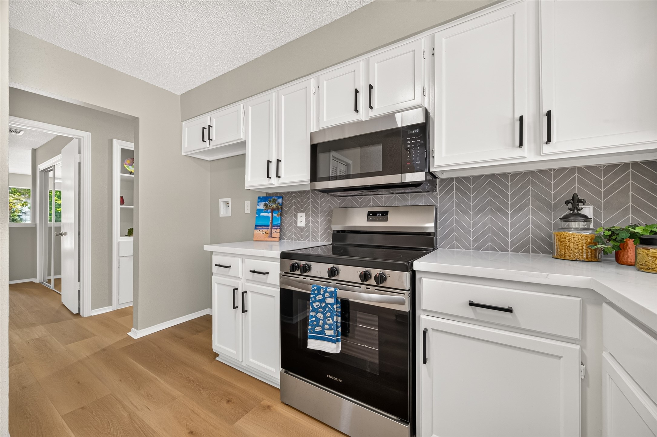 23219 Calico Corners Lane Spring, TX 77373 - Photo 5 of 24 Kitchen with sleek stainless steel appliances, elegant white cabinetry, and a stylish herringbone backsplash, offering a bright and inviting space.
